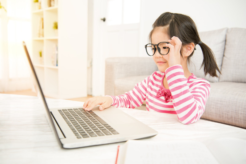 Young girl in glasses on laptop in living room
